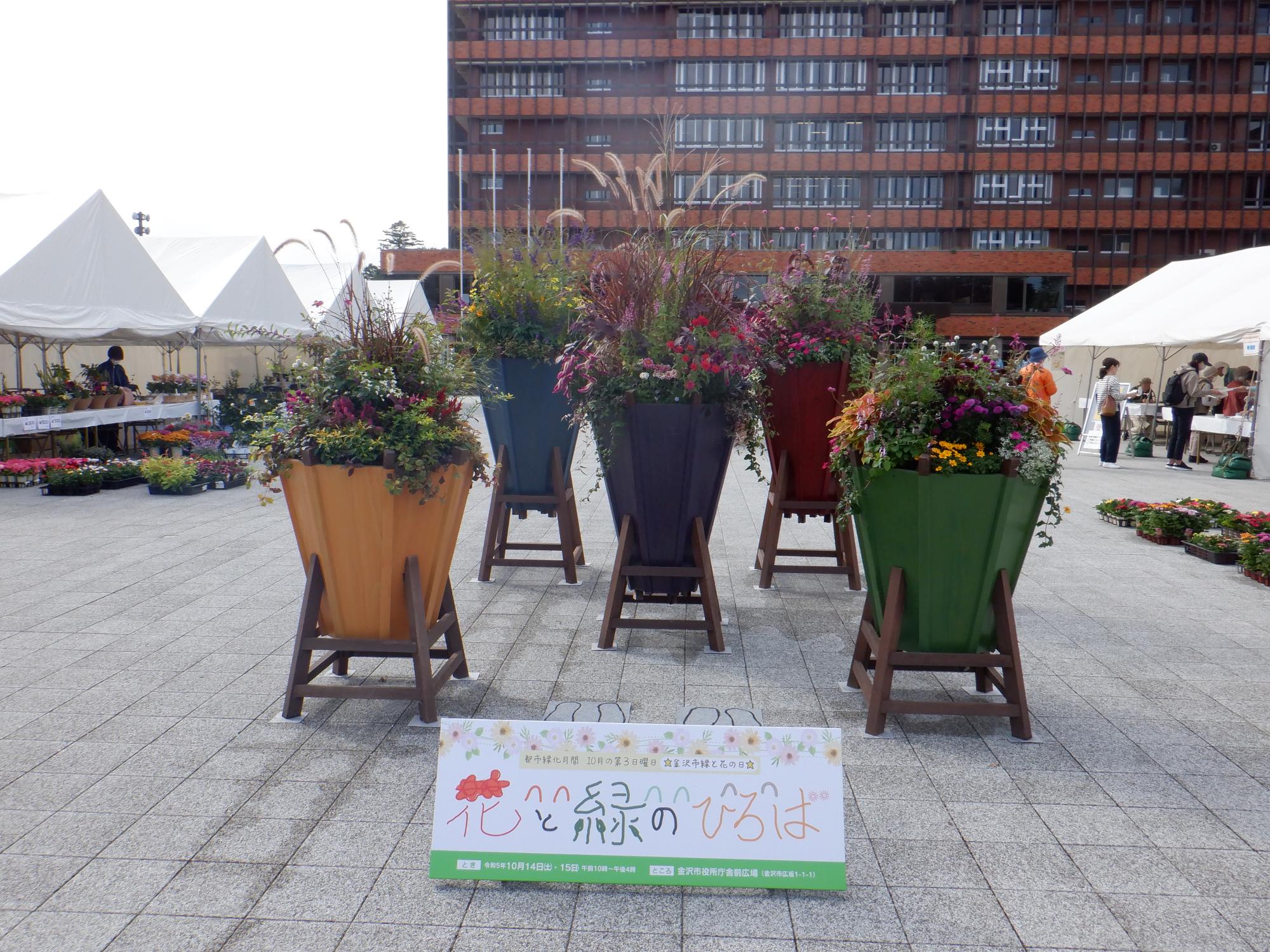 会場広場中央に大きな木材の鉢3個に緑が植えられている緑花フェスティバルの写真