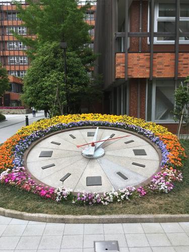 時計の数字の部分が大きさの違う四角になっており、色とりどりの花が時計の周りを一周して咲いている写真