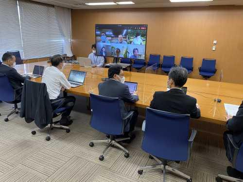 席の間に透明なアクリル板が設置された席に参加者達が座り、テレビの画面に写された参加者達と会議が行われている第2回金沢市DX会議の写真