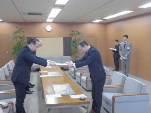 佐無田座長から市長へ報告書を手渡ししている写真
