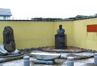 黄色い塀に囲われた鈴木大拙先生生誕記念碑の写真