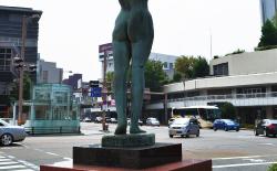 武蔵地区再開発の竣工記念として建てられた、萬生如意の女性像越しに車が行き交う様子の写真