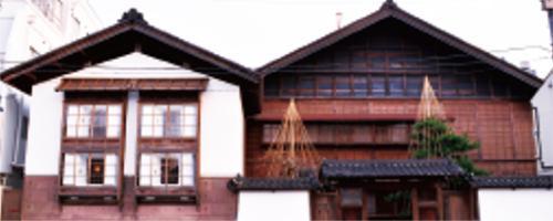 左側には白い壁で造られた和風の家、右側には茶色い壁で造られた和風の家が2軒並んでいる写真