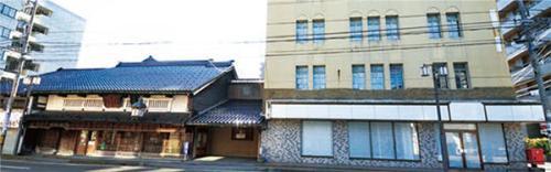 左側には瓦屋根の日本風の建物、右側には白いビルのような洋風の建物が建っている写真