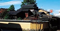 クリーム色の外壁に囲まれた2階建ての日本家屋の写真