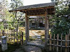 木戸門の奥に露地(茶庭)と下屋が見える写真