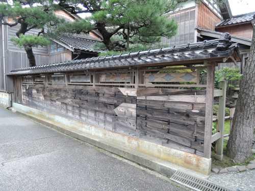 北端間に両開戸を吊り、他間は欄間を付し、舟板を横に張った観田家住宅西塀の写真