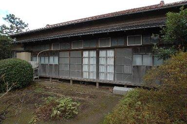 赤茶色の屋根の木造平屋で、ガラス戸と雨戸がある飯田家住宅側面の写真