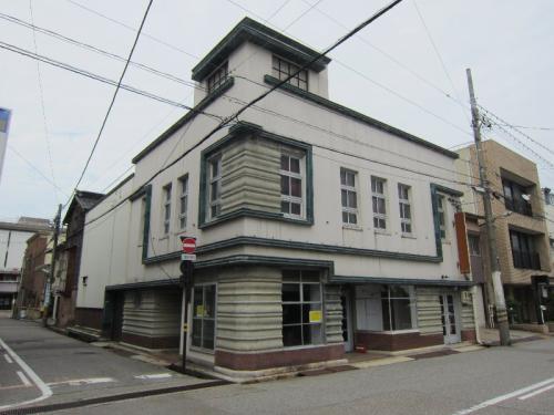 鉄筋コンクリート2階建の白壁、パラペット頂部の旧村松商店の写真