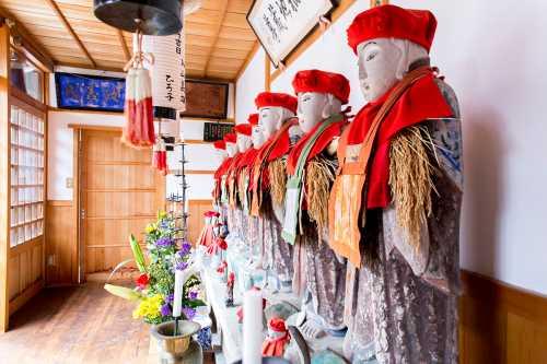 寿経寺門前の堂内にある赤い頭巾に前掛けをしたお地蔵様7体を横から撮影した写真