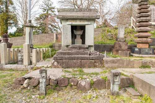 石の土台が積み上げられた上にある冨田重政の孫娘の石廟の写真