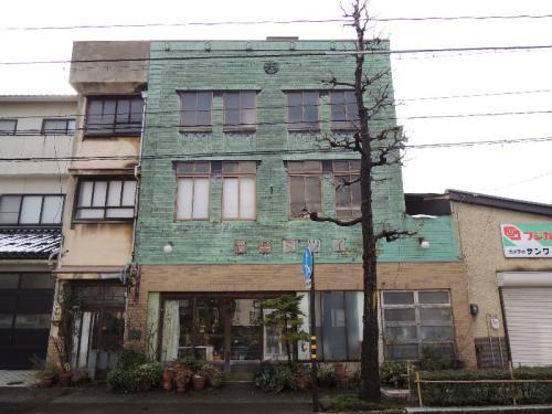 1階部分はタイル貼り、2階・3階部分を緑色の銅板張りで作られた角島家住宅店舗及び主屋の外観写真