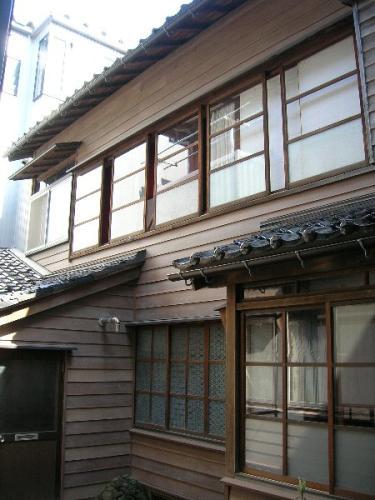 木造2階建て、瓦の屋根と昔ながらのガラス戸のある、上野家住宅主屋の写真