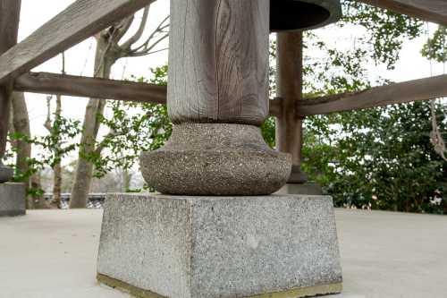 四角い石の土台の上にある鐘楼の粽付き円柱の写真