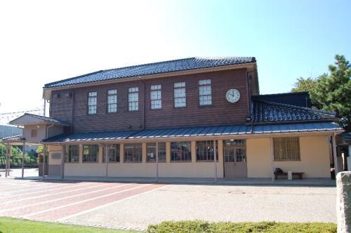 2階右側の外壁に丸い時計が掛かっている、木造二階建て「金沢市民芸術村事務所棟」全体の外観写真