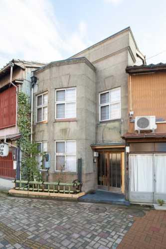 切妻造桟瓦葺の二階建てで、モルタル大壁洗出しの白い外壁の金沢町家兼六外観写真