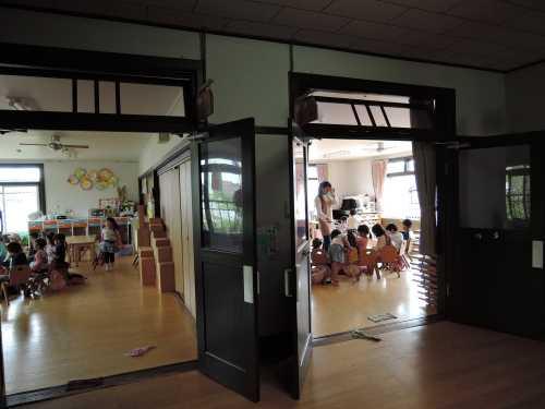 川上幼稚園園舎内2階ホールにて、保育士の下にたくさんの園児たちが集まっている様子の写真