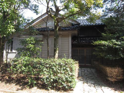白壁に三角屋根の旧石川県警察本部長公舎の前に木々がある写真