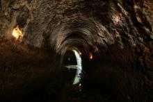 全体が薄暗く、辰巳用水上流部の隧道の所々に照明が付いている写真