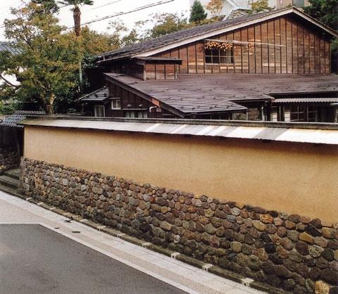 土塀の下半分が石積みされており、木造家屋や木々のある寺島蔵人邸跡の写真