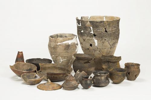 かけらをつぎはぎして復元された土器や所々かけている壺や皿などの中屋サワ遺跡出土品の写真