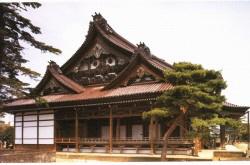 右側に大きな松の木がある、三角屋根の本願寺金沢別院本堂の写真