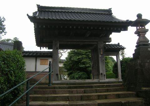 門の入口前に階段、右側には石灯篭がある本光寺山門の写真