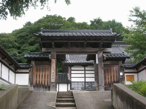 入口へと伸びている道の中央が階段になっており、高麗門形式の蓮昌寺山門から寺院が見えている写真