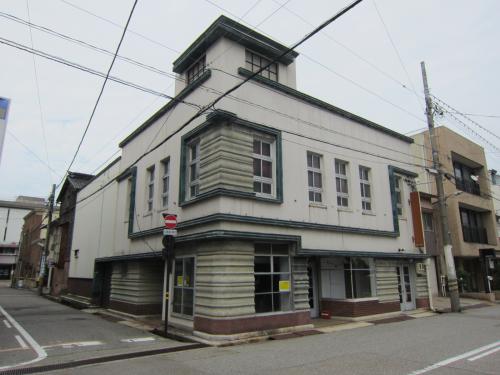 白が基調とされ緑で縁取りされた外壁の鉄筋コンクリート造2階建てのモダンな建物旧村松商店の外観写真