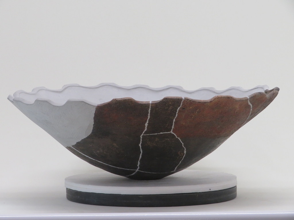 バラバラの状態から欠損部を白い樹脂で埋め元の形になるように接合した土器の写真