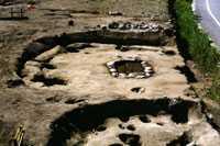 土が掘り起こされ、遺跡の後が形どられて、所々に大小の穴がある縄文時代の住居跡の写真