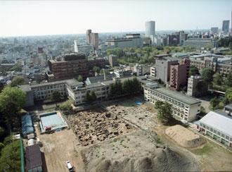 市内の一角の土地が掘り起こされ、遺跡調査が行われている様子を高い場所から写している広坂遺跡・全景写真