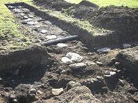 発掘調査のため掘られた地面の中に等間隔で白い礎石が並んでいる写真