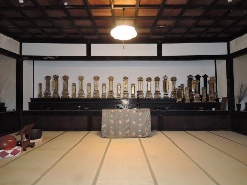 壁際の棚の上一面に位牌が置いてあり、手前に焼香台、左側に木魚がある御霊堂内部の写真