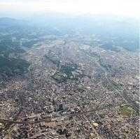 遠くには山々が連なり、住宅が広がっている金沢市街地の航空写真