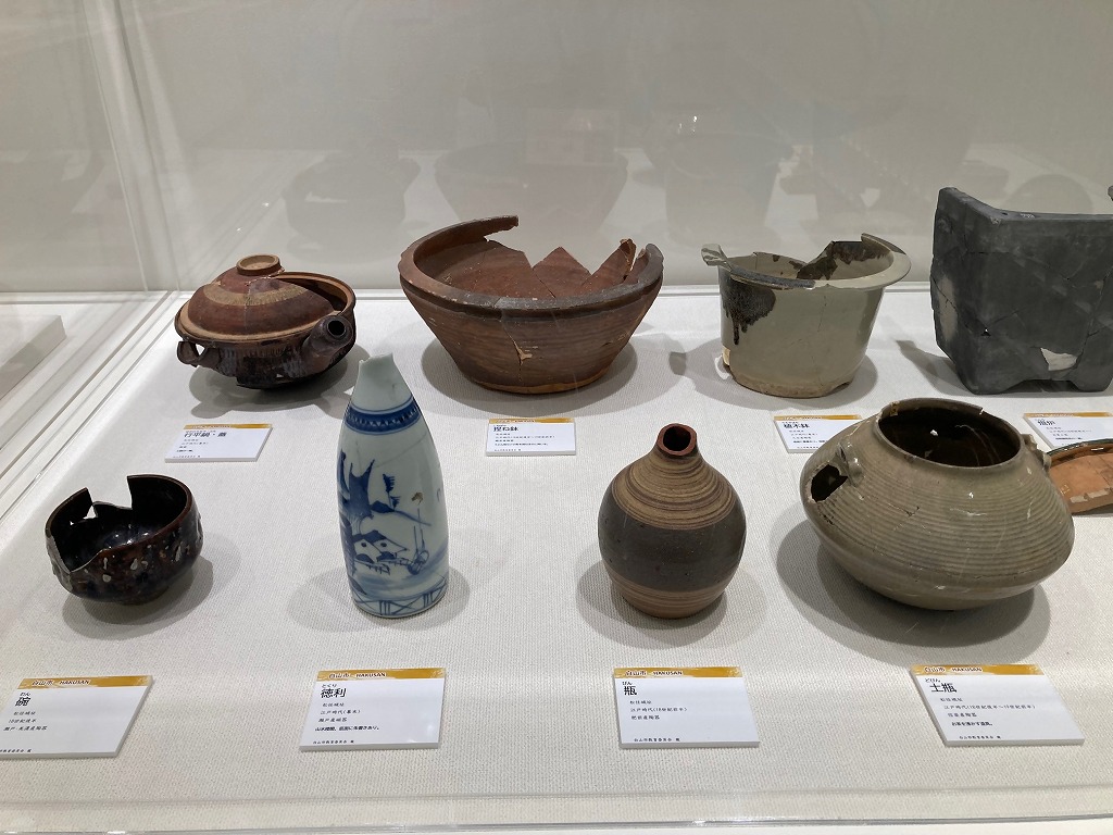 白山市松任城跡から出土した碗や徳利、土瓶などが並んでいる石川中央都市圏歴史資料展の展示風景