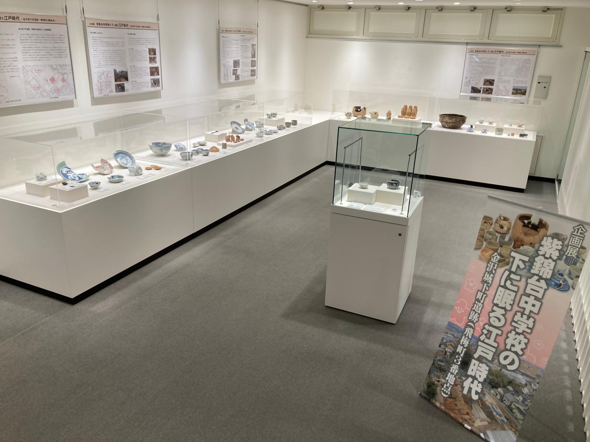 金沢縄文ワールド企画展示室の展示台に並ぶ合計80点の金沢城下町遺跡（飛梅町3番地点）出土品