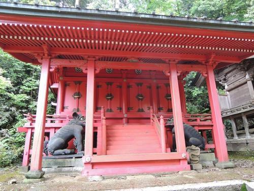 手前に狛犬が置かれている朱色の小坂神社本殿の写真