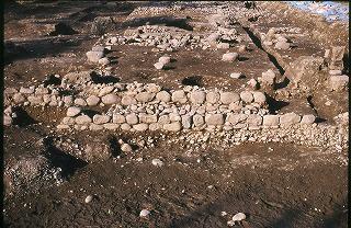 土が掘り起こされ、遺跡の後が形どられていおり、大小の石が積み重なって置かれている広坂遺跡・長屋門跡の写真