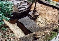 地面に穴を掘って前田利久のお墓前の堀を発掘している様子の写真
