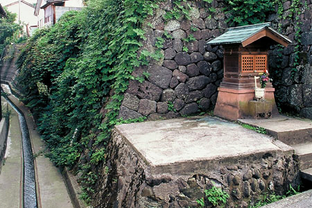 石造りの堀の手前に小さな祠があり、左側に細い水路が流れている東外惣構堀の写真