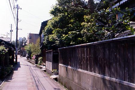 細い通りの右側に昔ながらの土塀が残る民家が建ち並ぶ閑静な武士系住宅地の写真