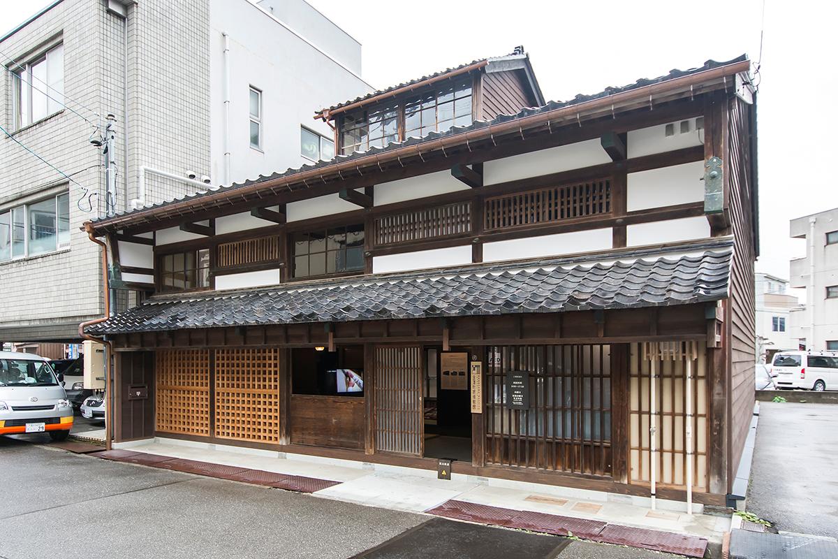 昔ながらの土壁や門が施されている民家の入り口付近の白黒写真