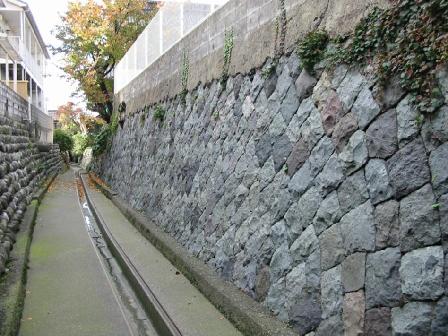 両側に高い石塀で挟まれた、奥まで真っすぐ続く細い水路の写真