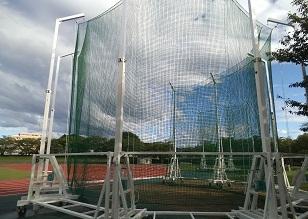 陸上競技場の隅に設置されたネットが張られたハンマー投用囲いの写真