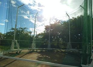 木々に囲まれた陸上競技場に設置されたハンマー投用囲いを正面から写した写真