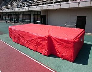 陸上競技場に設置された赤色のシートの走り高跳び用マットの全体を写した写真