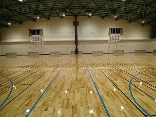 照明の光が床に反射している改修工事後の体育館内の写真