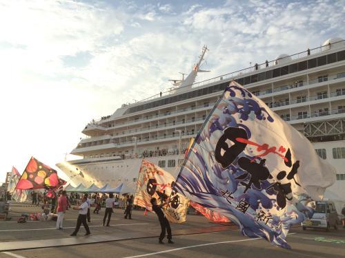 金沢港に入港したクルーズ船に大漁旗で歓迎している港の人達を写した写真