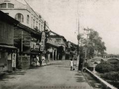道路左側に建物が立ち並ぶ並木町の白黒写真